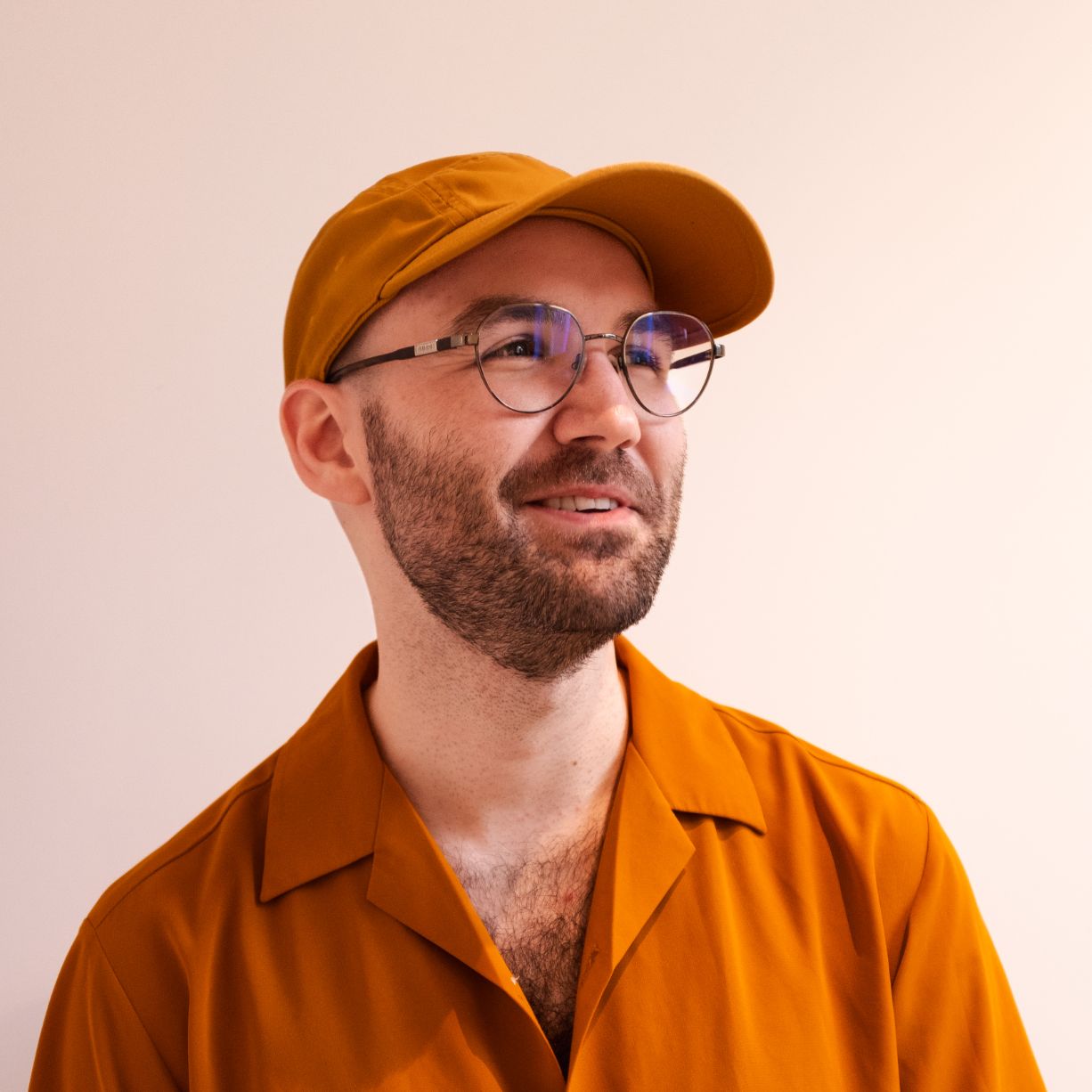 Marius J. Davidsen Portrett av mann med skjegg og briller, ikledd okergul skjorte og gul caps